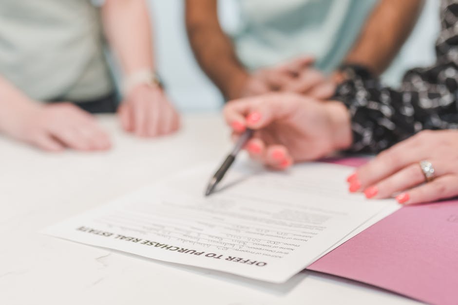 Close-up of people reviewing and signing an offer to purchase real estate document