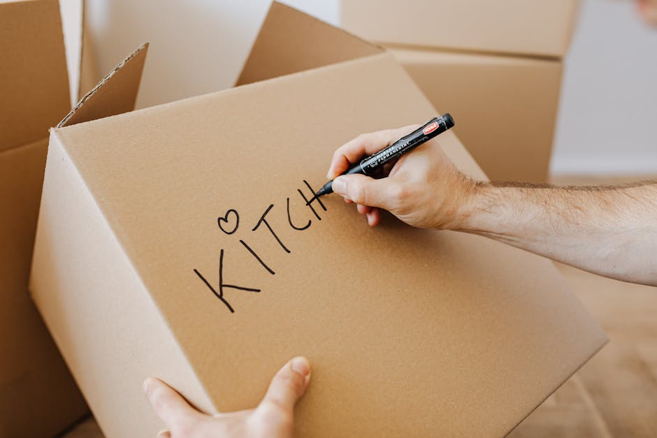 Person labeling moving boxes with marker for organized packing