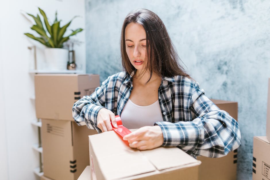Woman carefully sealing moving boxes with tape during home relocation