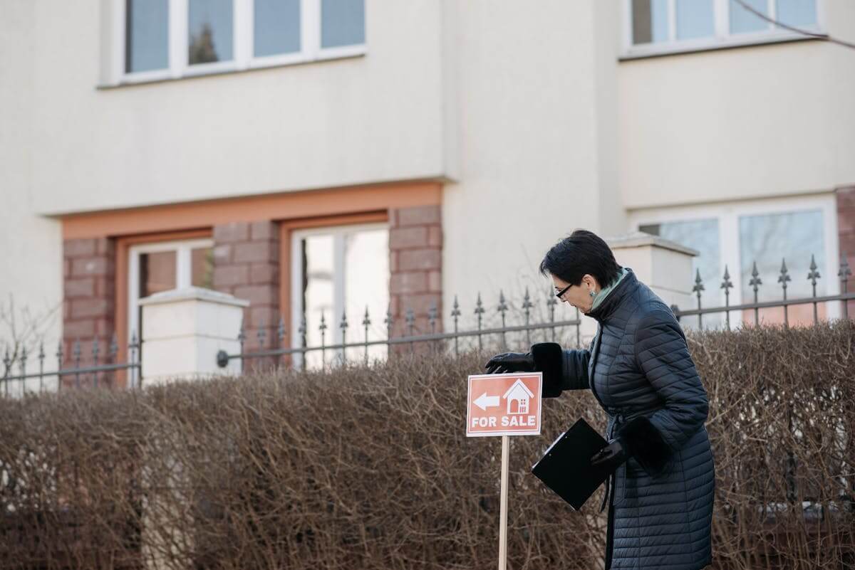 Real estate agent placing a for sale sign in front of a house before listing on the MLS