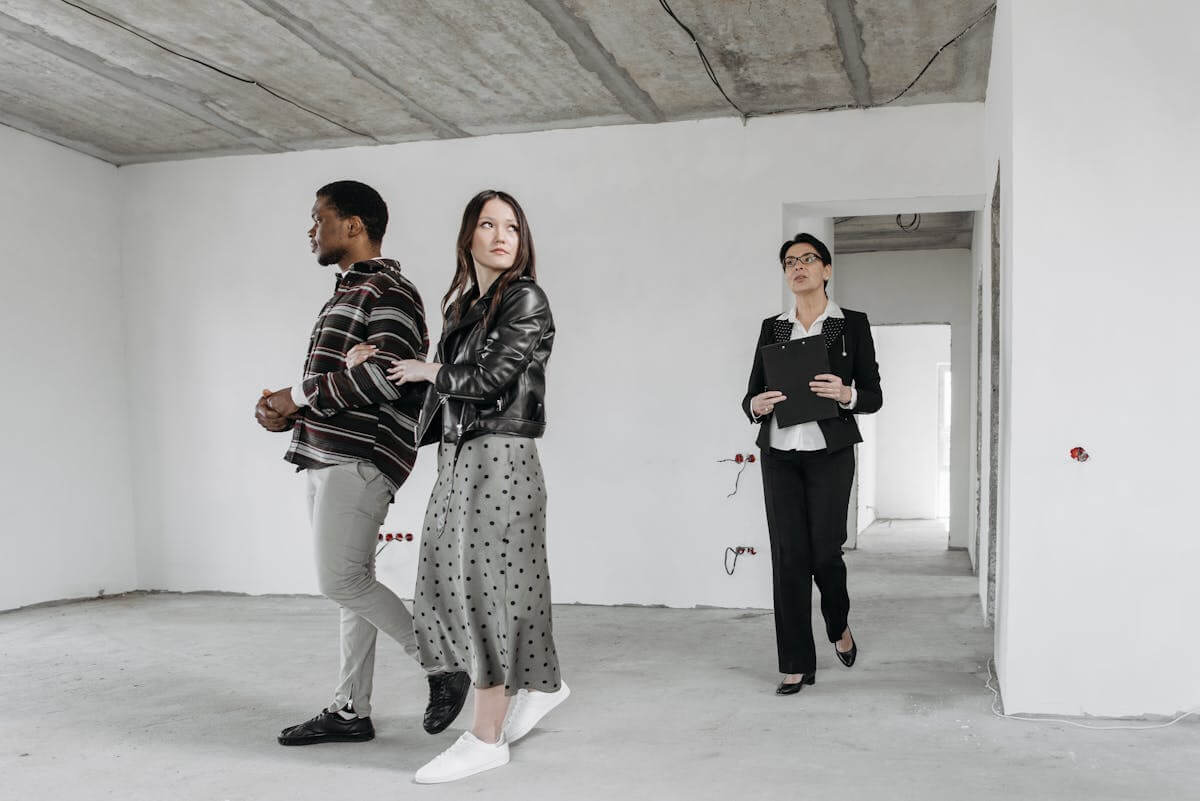 Real estate agent showing buyers an unfinished as-is property during a home tour