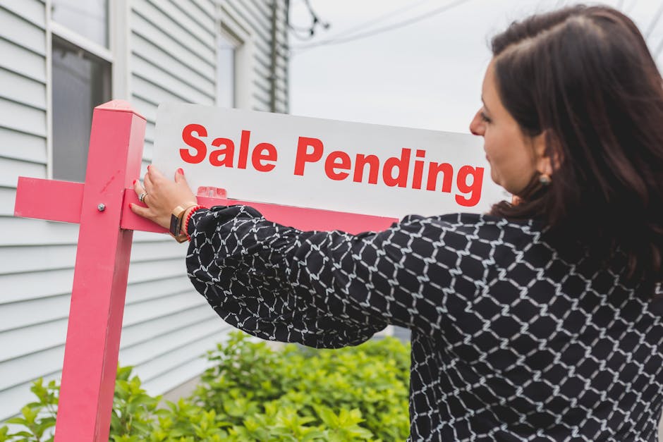 Real estate agent placing a sale pending sign on a property