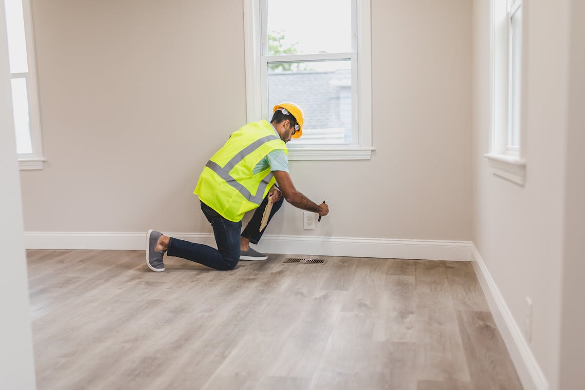 Home inspector in safety vest examining an electrical outlet during an as-is property inspection