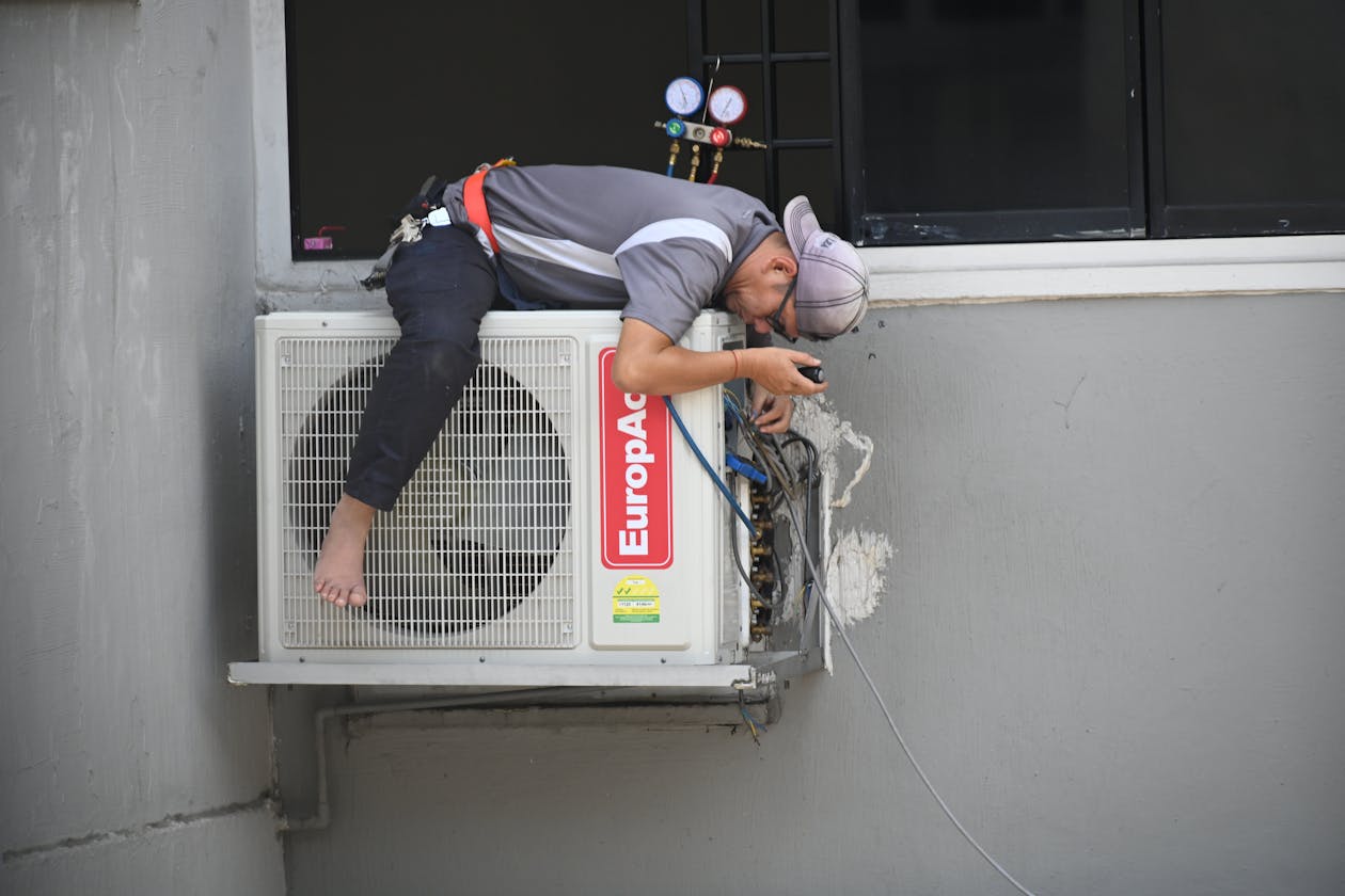 Technician repairing air conditioning unit covered by home warranty