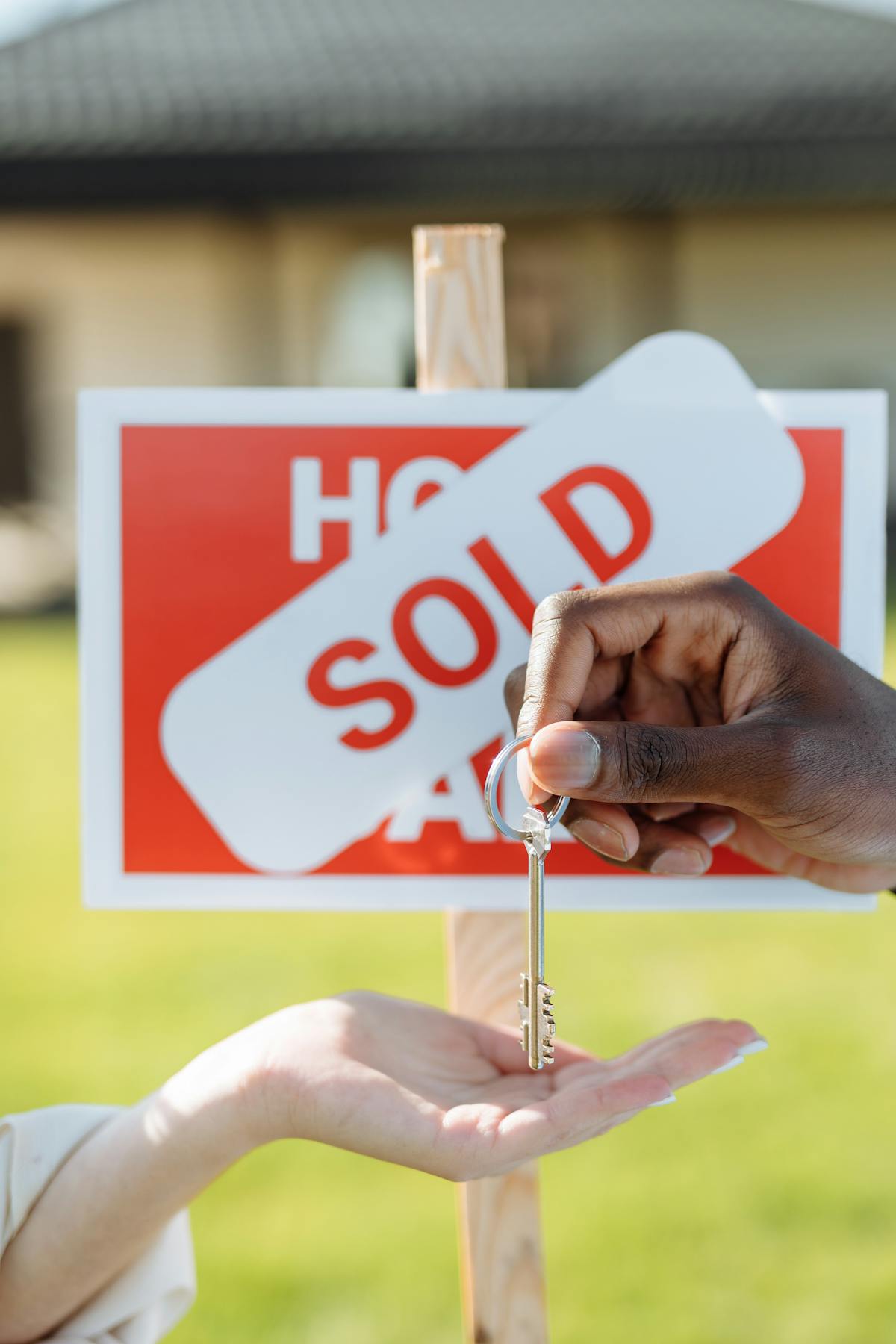 Key exchange in front of a sold sign, symbolizing successful real estate transaction