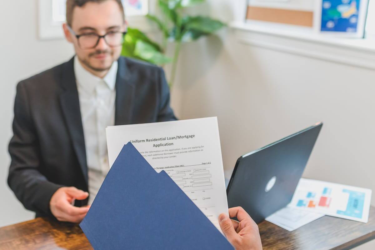 Mortgage broker and client discussing loan documents at a desk