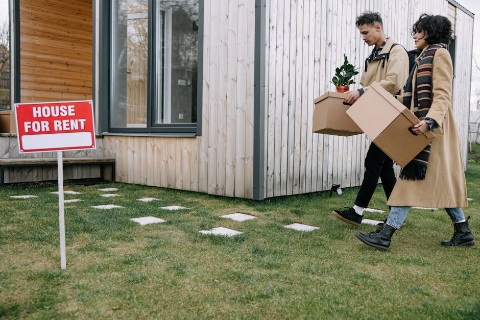 Young couple carrying moving boxes into their new home while deciding between renting and buying