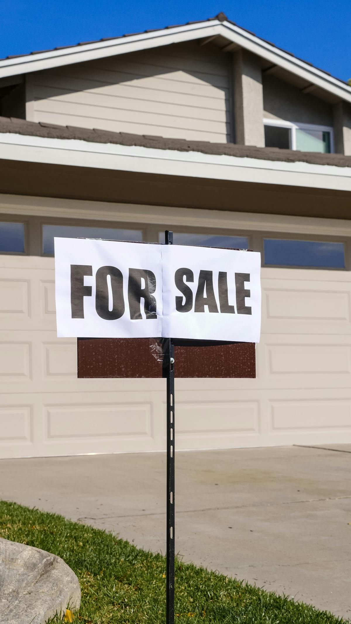 Modern suburban house with a for sale sign in the front yard during the contingent period of a real estate transaction