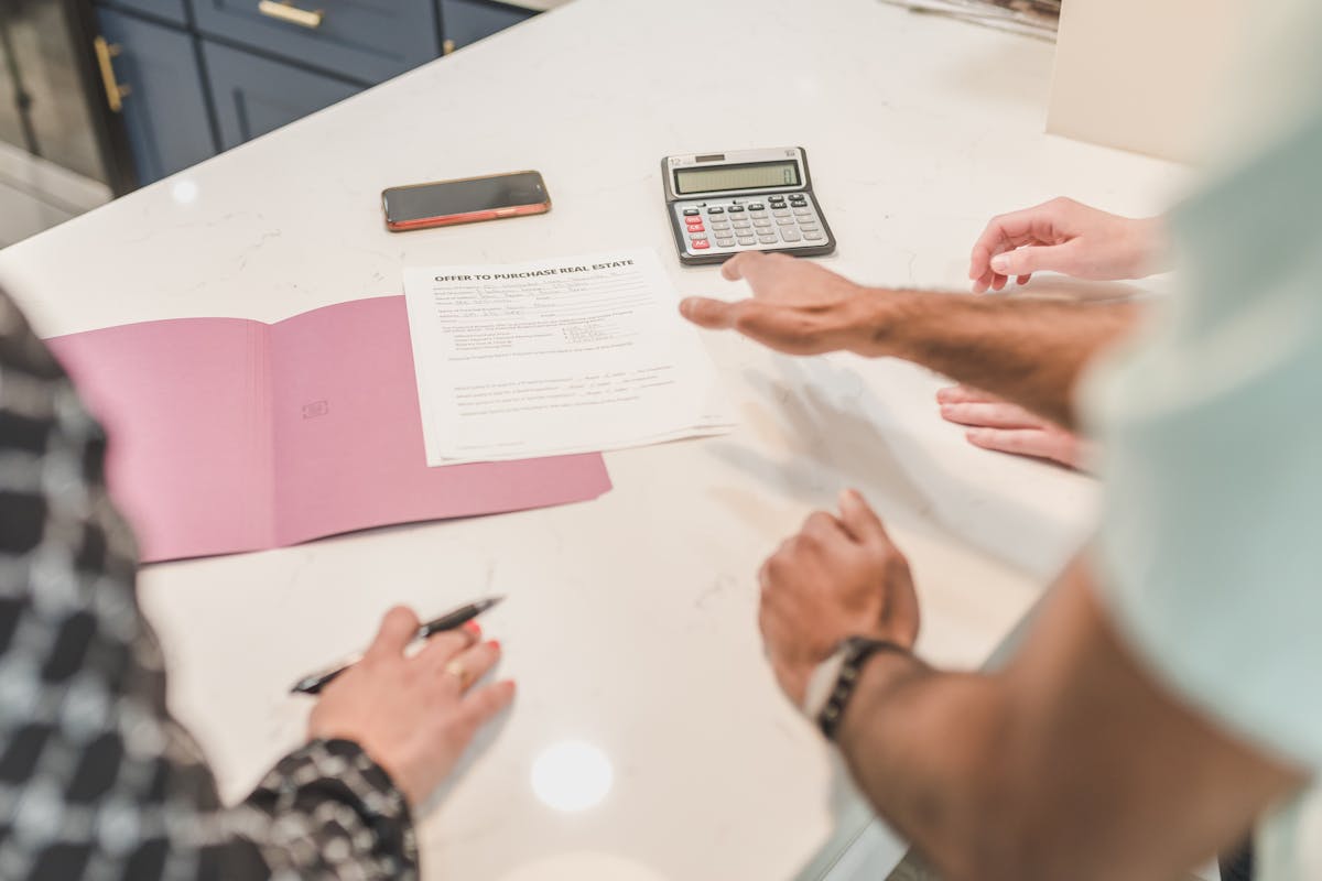 Close-up of hands reviewing real estate contingency documents on a desk with a calculator